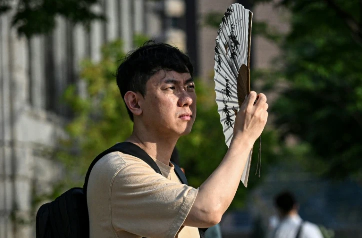 Un homme se protège du soleil avec un éventail, le 13 juillet 2026 à Séoul 