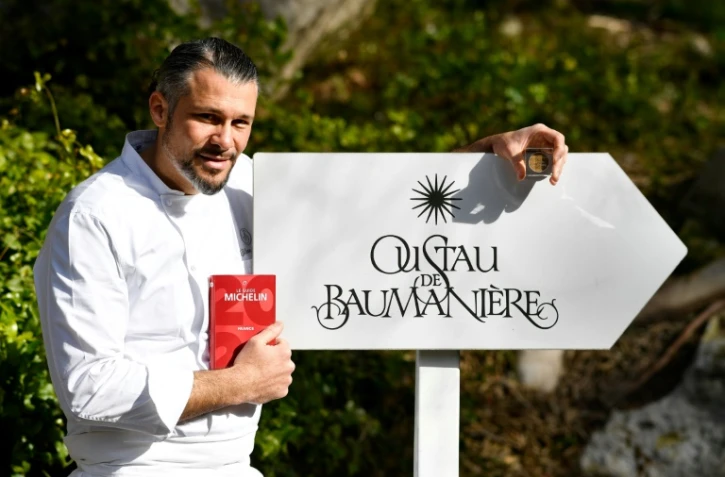 Glenn Viel pose avec le guide Michelin 2020 qui l'a consacré, le 29 janvier 2020 devant l'entrée de son restaurant aux Baux de Provence