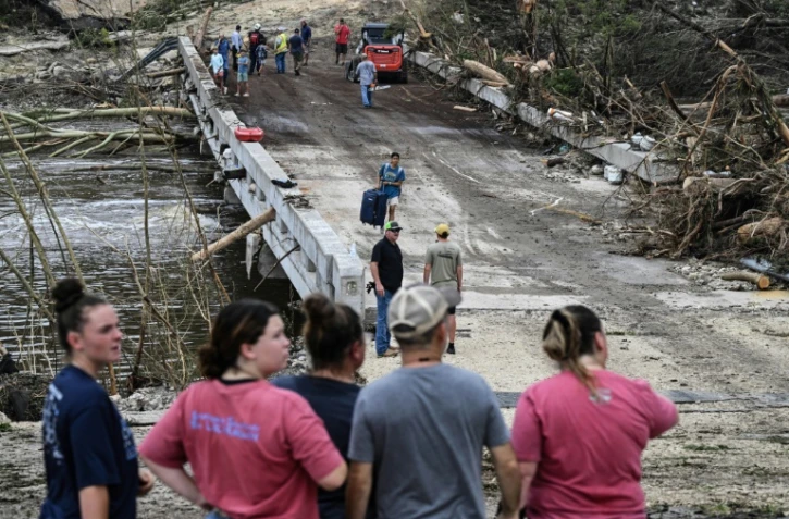 Des gens observent les secours qui recherchent des disparus près du camp d'été où 27 filles sont portées manquantes après des inondations subites à Hunt, dans l'Etat américain du  Texas,le 5 juillet 2025