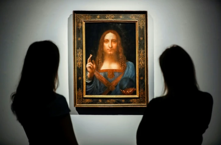 Des employées de Christie's devant le tableau attribué au maître italien Léonard de Vinci "Salvator Mundi", le 22 octobre 2017 à Londres, peu avant sa vente aux enchères