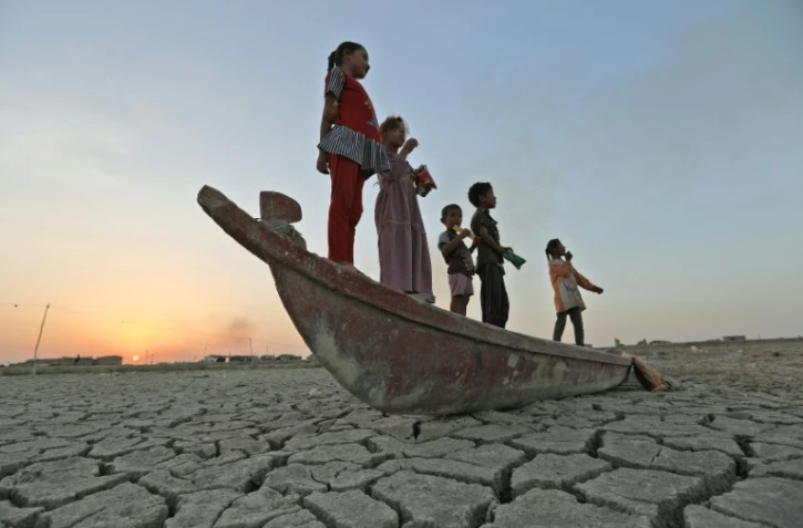 Des enfants jouent sur une barque dans les marais asséchés de Chibayich, dans le sud de l'Irak, le 24 juillet 2022