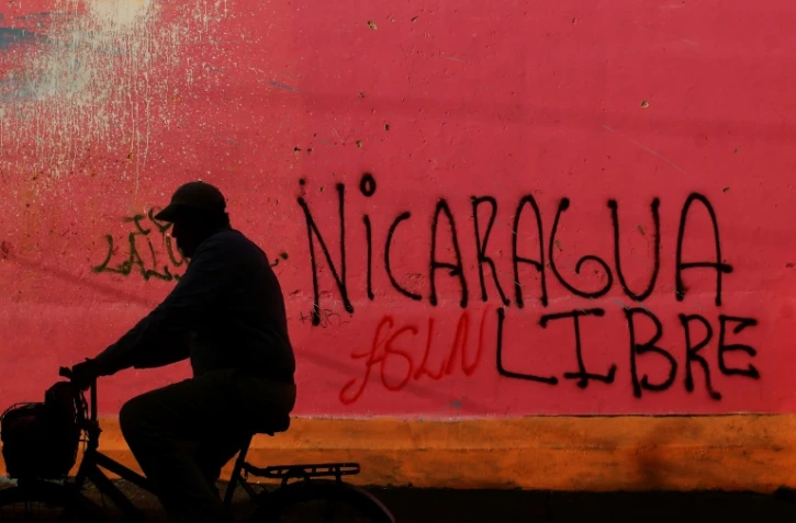 Un cycliste passe devant un graffiti réalisé au cours des manifestations contre le président Daniel Ortega, à Diriamba, à 40 km de Managua, le 124 juin 2018.