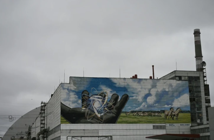 La centrale nucléaire de Tchernobyl et, en arrière plan, une partie du nouveau confinement de sécurité, un dôme métallique recouvrant le sarcophage du quatrième réacteur détruit lors de l'invasion russe de l'Ukraine, le 9 avril 2026 à Tchernobyl