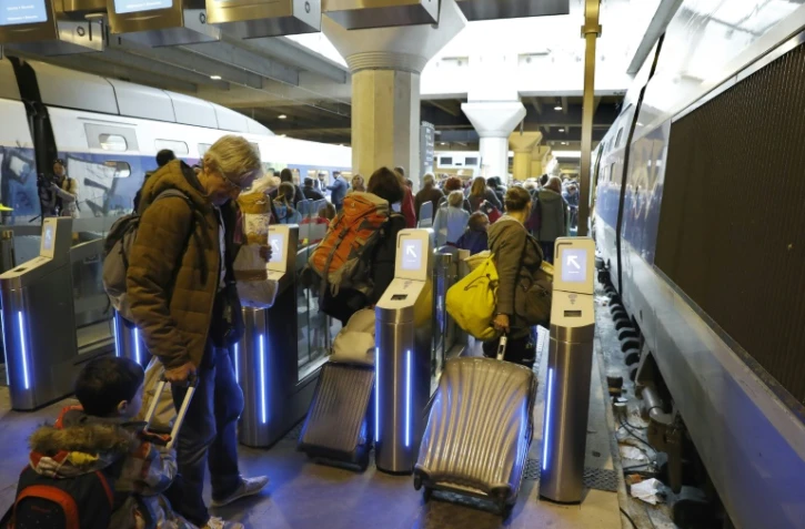 Des voyageurs passent des portes d'embarquement destinées à lutter contre la fraude à la gare Montparnasse le 3 avril 2017 à Paris