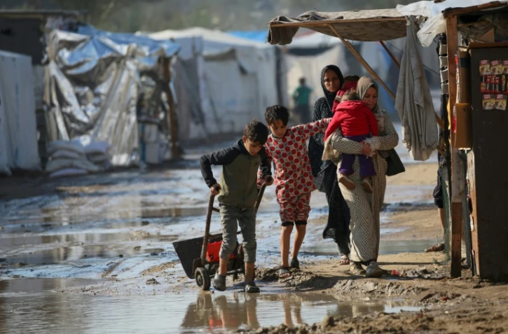 Des Palestiniens marchent dans une zone inondée après de fortes pluies dans un camp de déplacés à Deir el-Balah, dans le centre de la bande de Gaza, le 30 décembre 2024