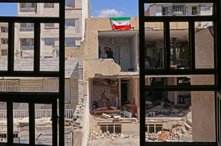 Un drapeau iranien sur un immeuble détruit à Vahdat, au sud-ouest de Téhéran le 3 avril 2026