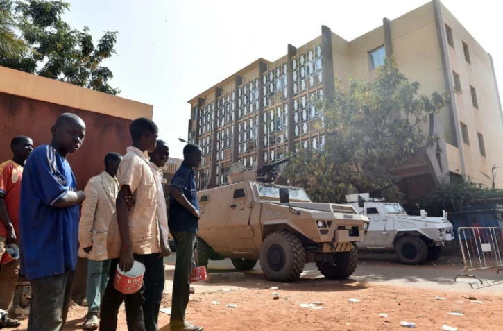 Des personnes se tiennent à côté d'une barrière près de l'hôtel Splendid le 17 janvier 2016 à Ouagadougou