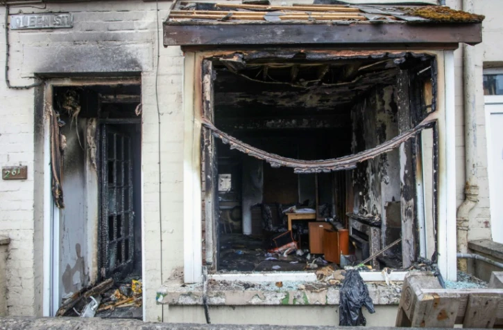 L'entrée et la fenêtre d'une maison brûlées après une deuxième nuit d'émeutes visant des immigrés à Ballymena, le 11 juin 2025 en Irlande du Nord