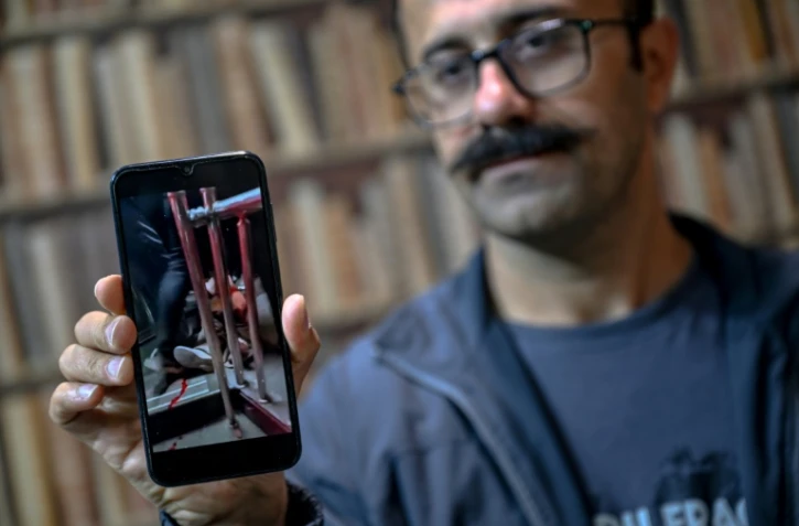 Farhad Sheikhi, un Kurde iranien qui a rejoint les manifestations antigouvernementales en 2022, montre des images des manifestations en Iran lors d'une interview à Souleimaniyeh, le 12 mars 2026 en Irak