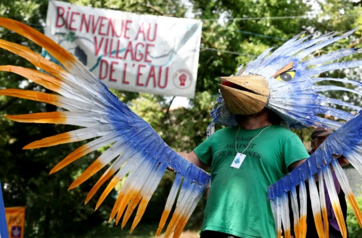 Un homme déguisé en oiseau accueille les participants au "Village de l'eau", près de Saint-Martin-lès-Melle, le 16 juillet 2024