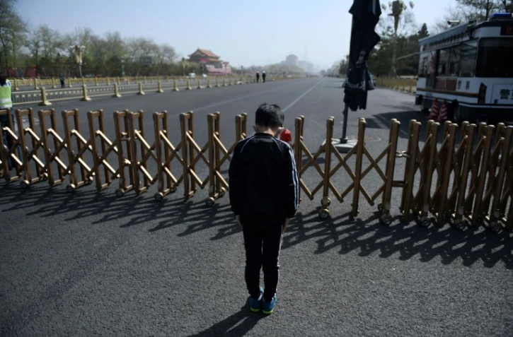 Un jeune garçon rend hommage aux morts du coronavirus lors d'une moment de recueillement national, à Pékin place Tiananmen, le 4 avril 2020