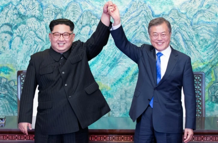 Le président sud-coréen Moon Jae-in (d) et le leader nord-coréen Kim Jong Un main dans la main à l'issue du sommet intercoréen, le 27 avril 2018 à Panmunjom