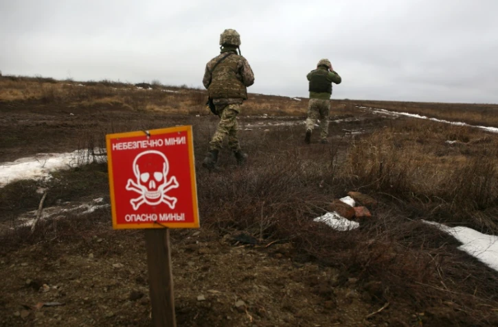 Des militaires ukrainiens patrouillent près d'un champ de mines sur la ligne de front, le 11 janvier 2021 à Luganske, dans la région de Donetsk