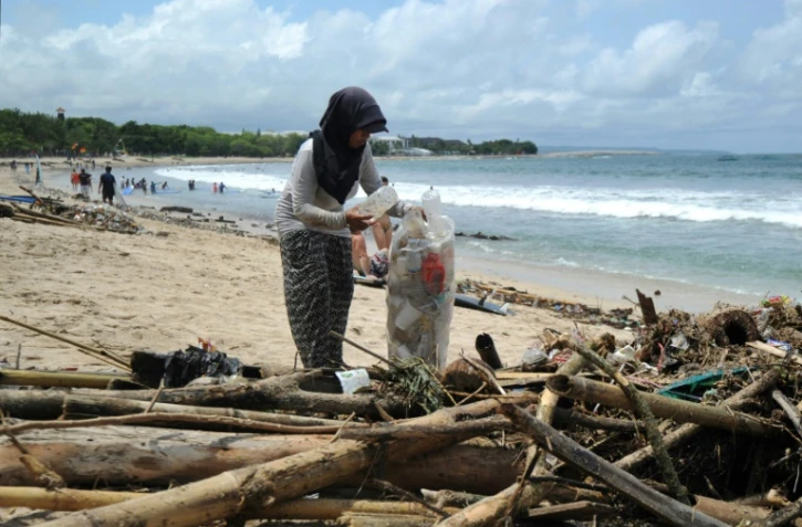 Une femme collecte des déchets plastiques sur une plage, le 9 décembre 2018 à Bali