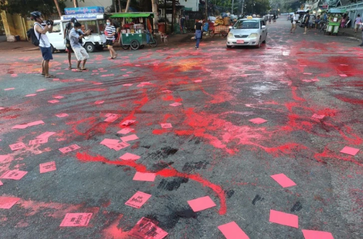 Photo fournie par une source anonyme de manifestants à Rangoun, le 10 avril 2021 maculant la rue de peinture rouge et distribuant des flyers pour dénoncer le coup d'état militaire