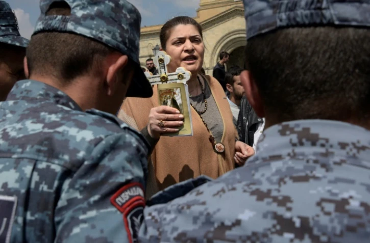 Une Arménienne brandit une croix devant des policiers anti-émeutes lors de manifestations antigouvernementales dimanche 22 avril à Erevan.