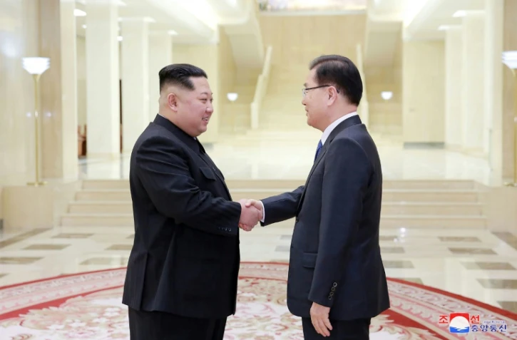 Photo fournie le 6 mars 2018 par l'agence nord-coréenne Kcna du leader nord-coréen Kim Jong-Un (g) et du conseiller du président sud-coréen Chung Eui-yong (d), lors d'une rencontre le 5 mars 2018 à Pyongyang 