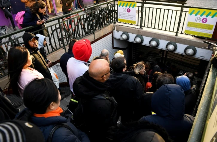 Des voyageurs attendent que les grilles du métro s'ouvrent le 20 décembre 2019 à la station Porte d'Orléans à Paris