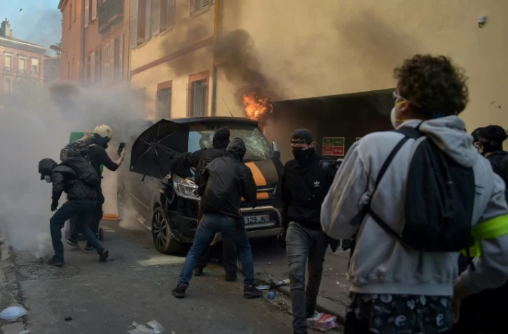 Des "gilets jaunes" affrontent la police près d'un véhicule incendié à Toulouse le 13 avril 2019, pour l'"acte 22" du mouvement.