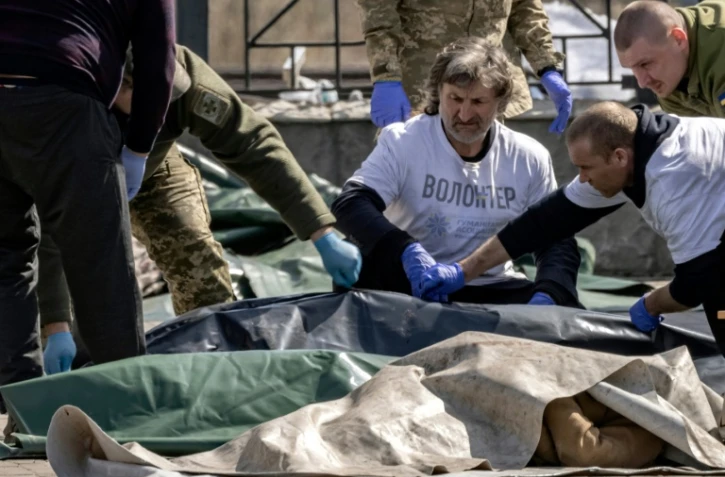 Des soldats ukrainiens enveloppent les corps des victimes d'une attaque de missiles russes sur la gare de Kramatorsk, le 8 avril 2022 dans la régin du Donbass, dans l'est de l'Ukraine