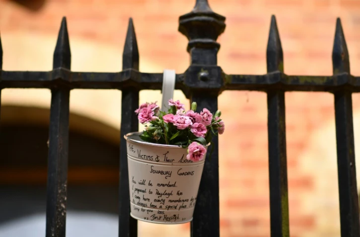 Des fleurs en hommage aux victimes sont accrochées à une grille le 21 juin 2020 à Reading, ville à une soixantaine de km de Londres, près d'un parc où s'est produite la veille une attaque meurtrière au couteau