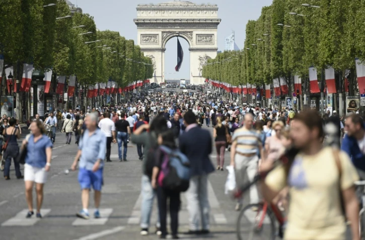 Des passants sur l'avenue des Champs-Elysées à Paris le 8 mai 2016 à l'occasion d'une journée sans voiture désormais chaque premier du dimanche du mois pour lutter contre la pollution