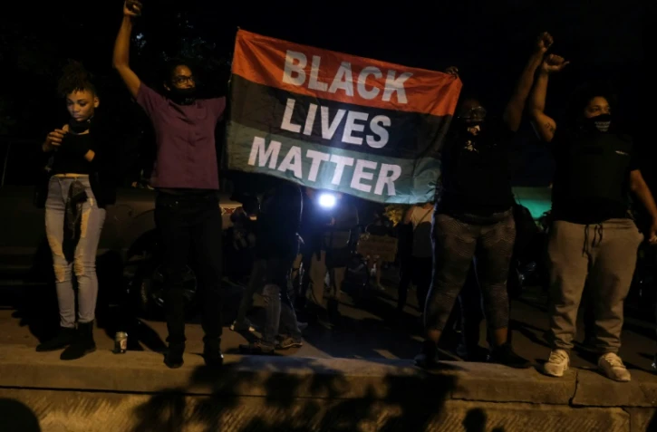 Des manifestants tiennent un drapeau "Black Lives Matter" devant la First Unitarian Church, le 25 septembre 2020 à Louisville, dans le Kentucky
