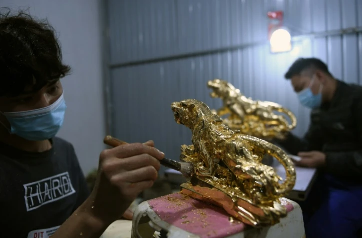 Un artisan recouvre de feuilles d'or une figurine de tigre dans un atelier à Hanoï, au Vietnam, le 19 janvier 2022 
