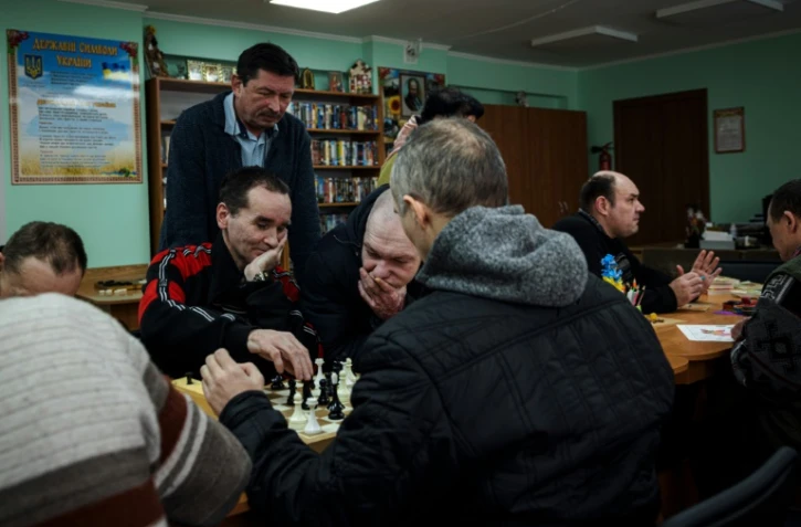 Viktor Jouravski (debout), directeur de la pension neuropsychiatrique pour hommes de Novo-Bilytsky regarde des patients jouer aux échecs, le 12 mars 2022 à Kiev