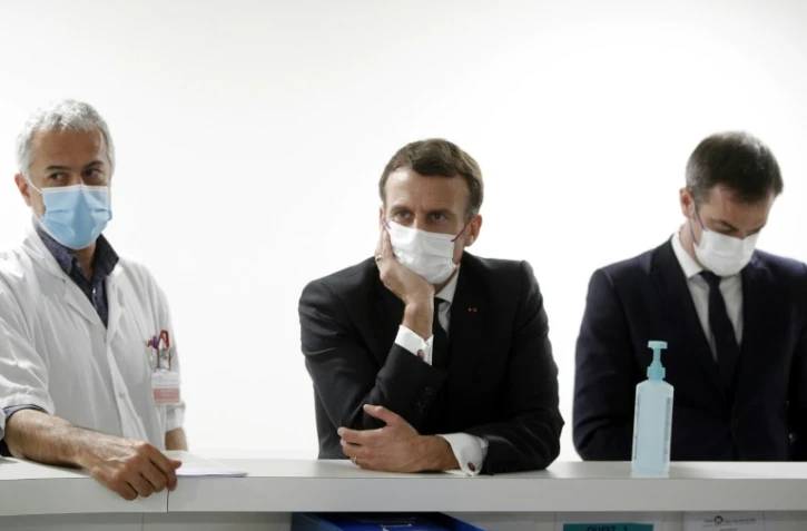 Le président français Emmanuel Macron (au centre), le ministre de la Santé Olivier Veran (à droite) et Jan Hayon (à gauche), le médecin chef des soins intensifs de l'hôpital de Poissy (France), discutent avec le personnel soignant, le 17 mars 2021