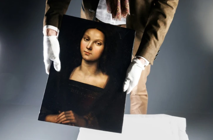 Un homme présente un portrait de Marie-Madeleine attribué au peintre et architecte italien de la Renaissance Raphaël, le 21 octobre 2023 à Paris