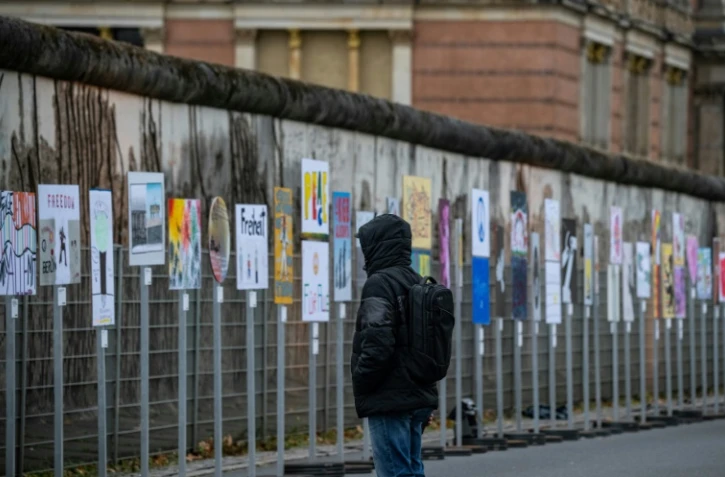 Un homme regarde des pancartes installées le long de l'ancien tracé du Mur de Berlin vendredi 8 novembre, en vue des célébrations des 35 ans de la chute du Mur de Berlin, intervenue le 9 novembre 1989