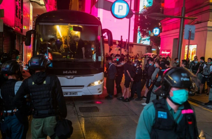 Des policiers arrêtent des manifestants contre la loi sur la sécurité imposée par la Chine et les font monter dans un bus, le 1er juillet 2020 à Hong Kong