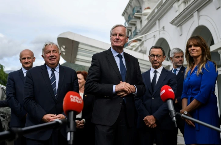 Le Premier ministre français Michel Barnier (C) s'adresse aux journalistes après avoir été accueilli par le chef du groupe parlementaire du parti Les Républicains (LR) au Sénat, à Paris, le 12 septembre 2024