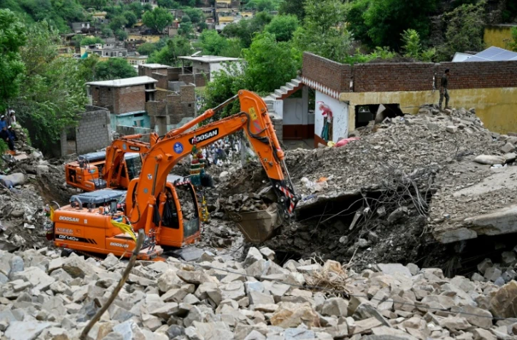 Des secouristes utilisent des pelleteuses pour dégager les décombres des maisons effondrées et rechercher des victimes dans les débris, à Dalori, dans la province montagneuse de Khyber Pakhtunkhwa, le 19 août 2025 au Pakistan