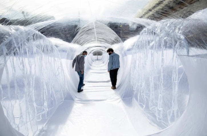 Deux hommes marchent dans un tunnel de plastique destiné à isoler les patients du covid le 16 février 2021 à Bogota