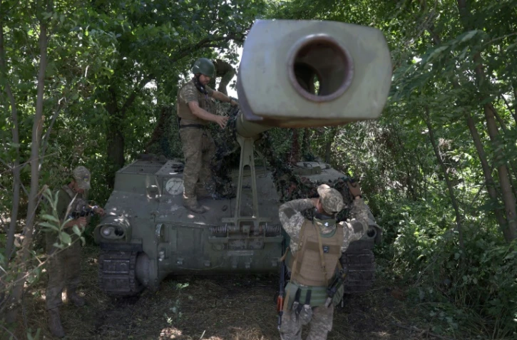 Des soldats ukrainiens installent un filet de camouflage sur un obusier automoteur M109 de 155 mm, le 10 juillet 2023 dans la région de Donetsk