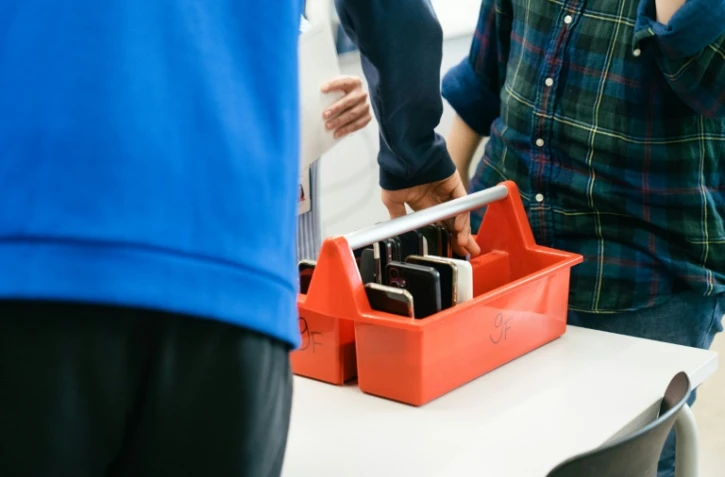 Un élève dépose son smartphone dans une boîte spéciale au début de la journée au collège Kungsvägens skola, le 21 août 2025 à Sipoo, en Finlande