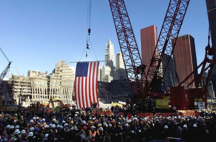Le drapeau américain suspendu à une grue au-dessus de "Ground Zero" lors d'une cérémonie commémorative, le 11 novembre 2001 à New York, sur le site du World Trade Center détruit par des attentats le 11 septembre 2001