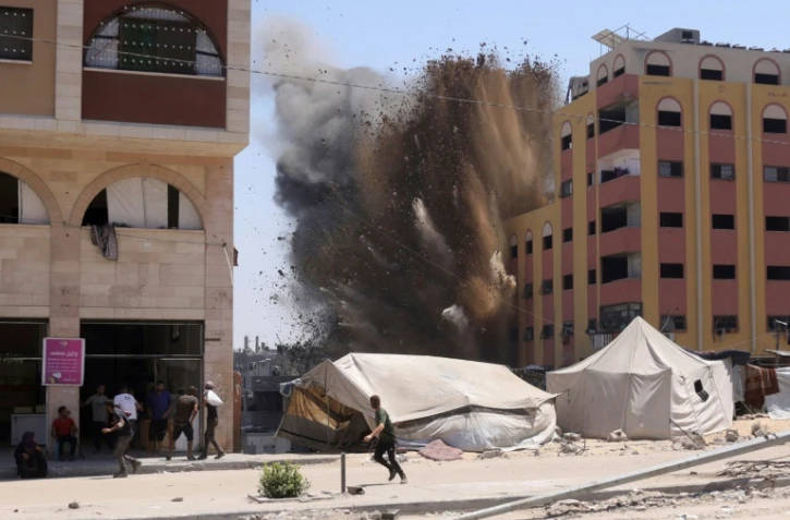 Des Palestiniens se précipitent pour se mettre à l'abri après qu'une frappe israélienne a touché un immeuble à proximité à Jabalia, dans le nord de la bande de Gaza, le 20 août 2025

