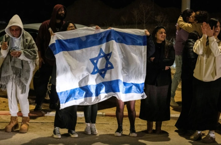 Des personnes brandissant des drapeaux israéliens accueillent l'arrivée des ex-otages du Hamas, le 1er décembre 2023 devant la base militaire d'Ofakim, dans le sud d'Israël