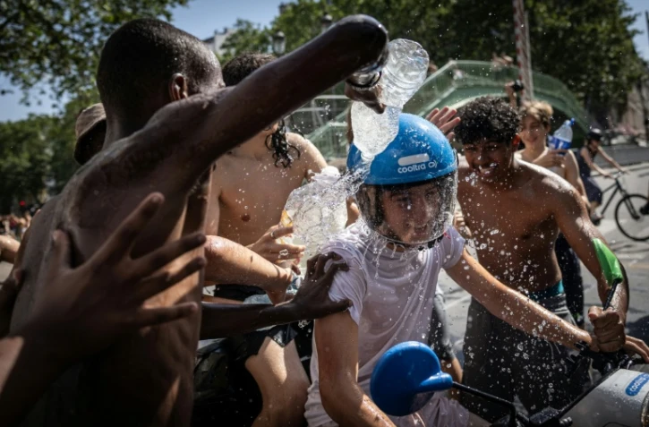 Un groupe d'adolescents asperge d'eau un jeune homme circulant en scooter près du canal Saint-Martin, à Paris, le 24 juin 2026