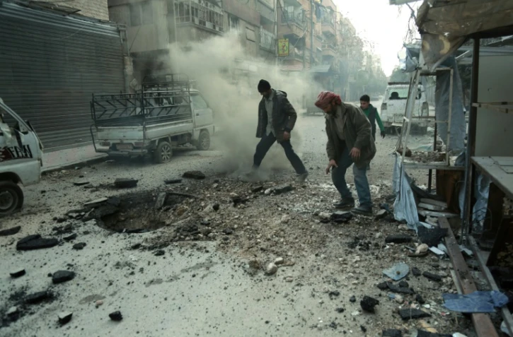 Des hommes constatent les dégâts après un bombardement du régime sur Douma, la principale ville de l'enclave rebelle dans la Ghouta orientae, le 10 mars 2018