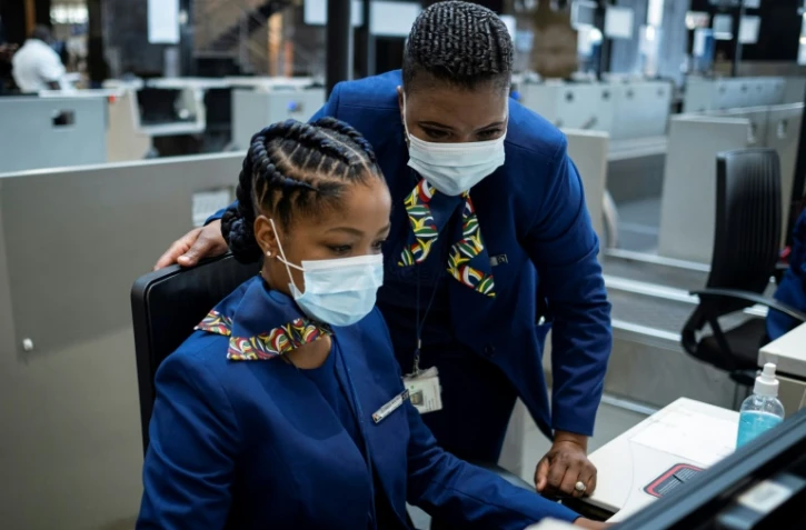 Des employés de la compagnie aérienne sud-africaine SAA au comptoir d'embarquement de l'aéroport international O.R. Tambo  de Johannesburg, le 23 september 2021