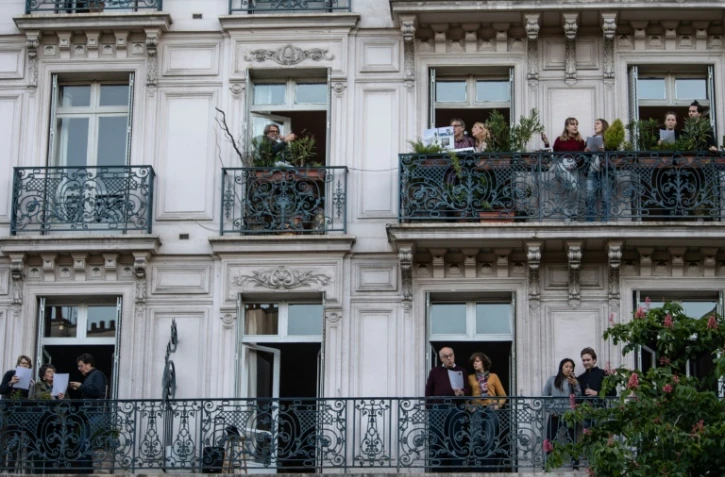 Des parisiens sur leur balcon chantent ensemble, le 1er mai 2020