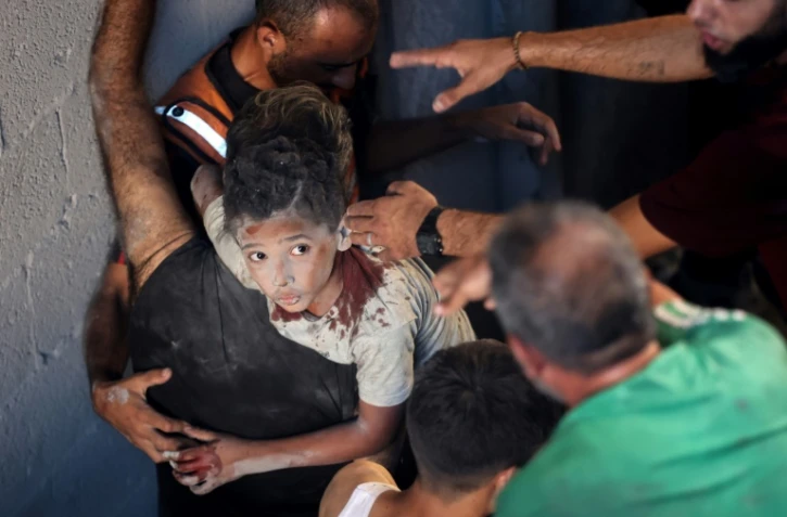 Des Palestiniens transportent un enfant blessé sur le site d'une frappe israélienne sur le quartier d'Al-Rimal à Gaza-ville, le 30 août 2025