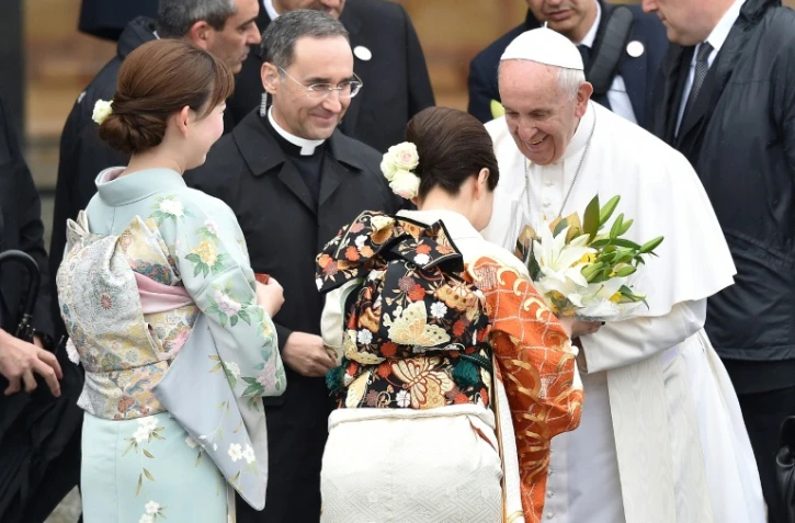 Le pape reçoit des fleurs offertes par des femmes en kimonos à son départ de l'aéroport de Tokyo, le 26 novembre 2019