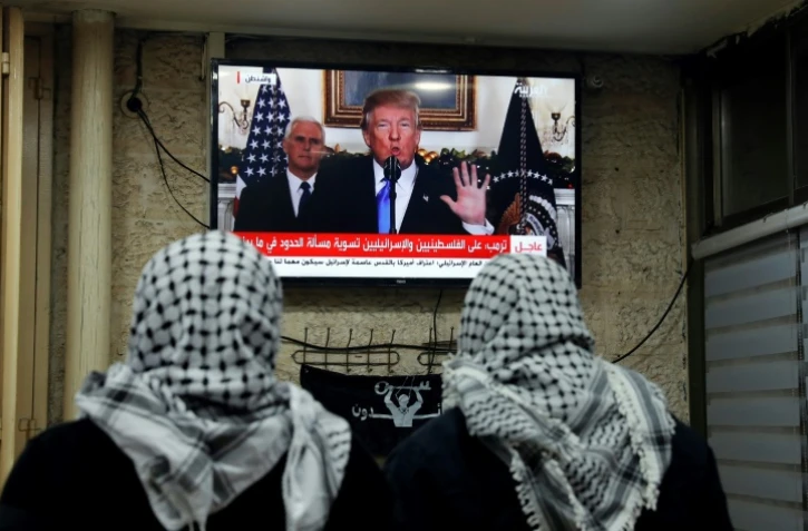 Deux palestiniens regardent le président américain Donald Trump reconnaître officielement Jérusalem comme capitale de l'Etat d'Israël le 6 décembre