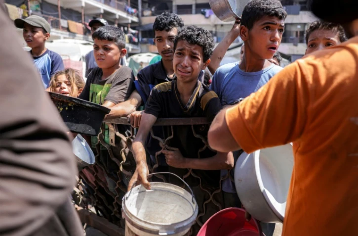 Des enfants palestiniens font la queue pour recevoir des repas d'une organisation caritative à Gaza-ville, le 14 juillet 2025