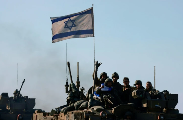 Des soldats israéliens de retour de Gaza dans un convoi blindé à la frontière en Israël et le territoire palestinien le 15 janvier 2024